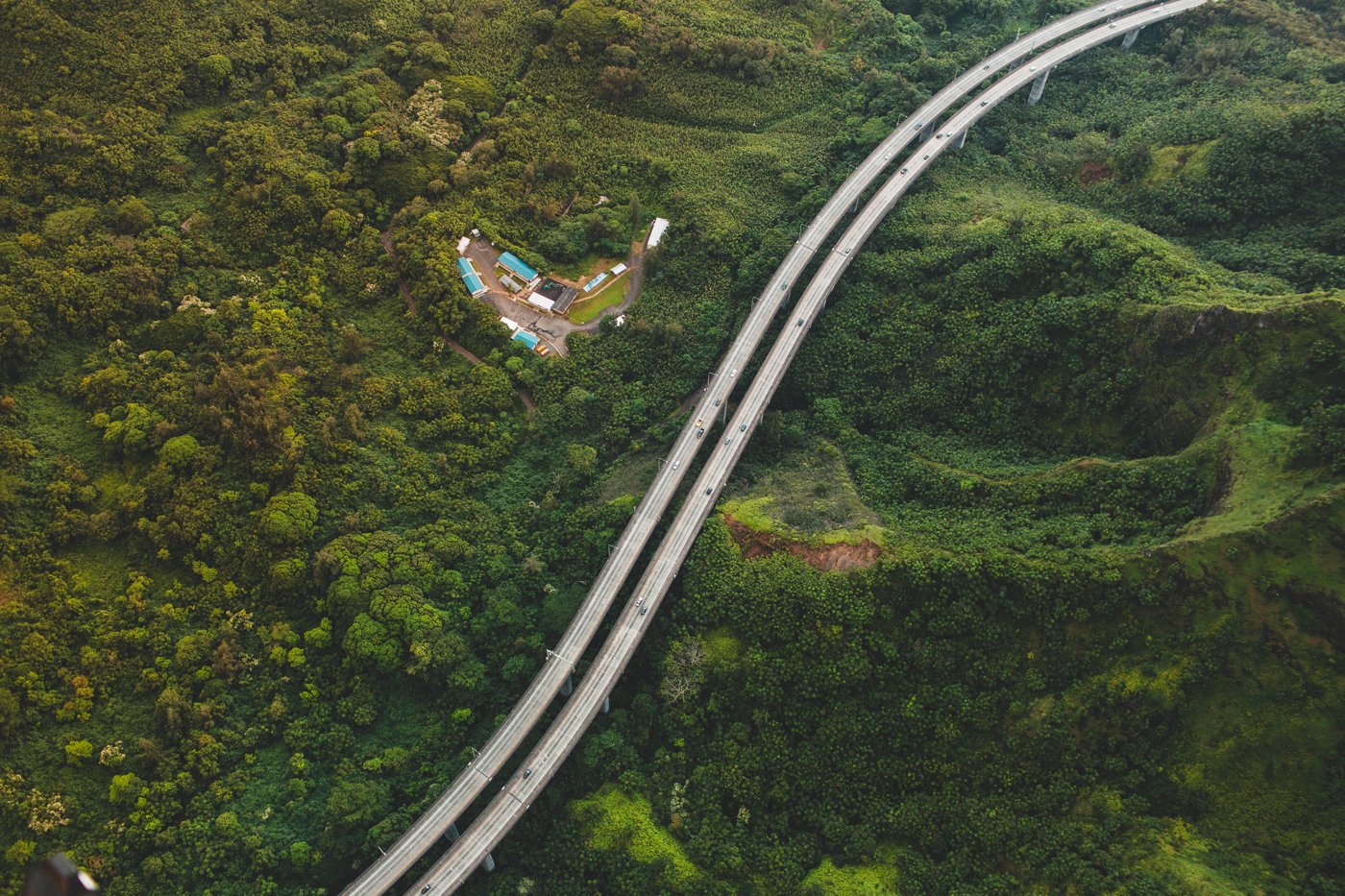 Aerial view of H-3 sweeping across a lush forested valley in Oahu's Koolau range